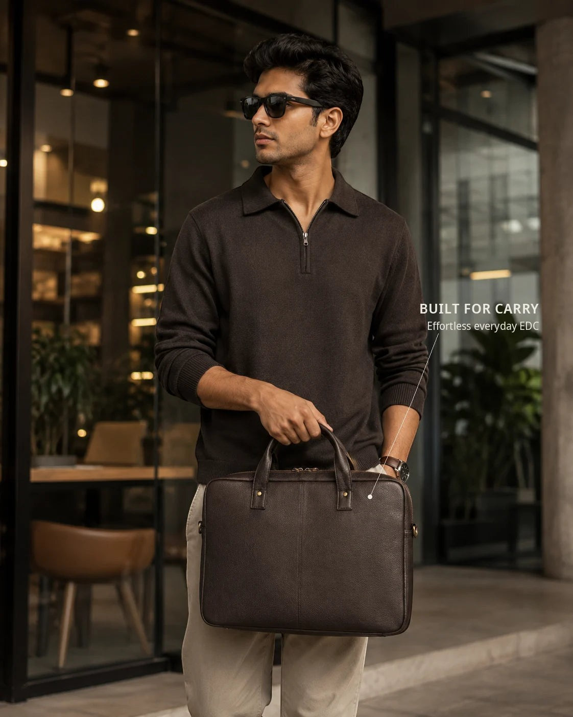 Wildebeast The Wayfarer slim dark brown pebbled leather work bag held by a man in a modern office setting.
