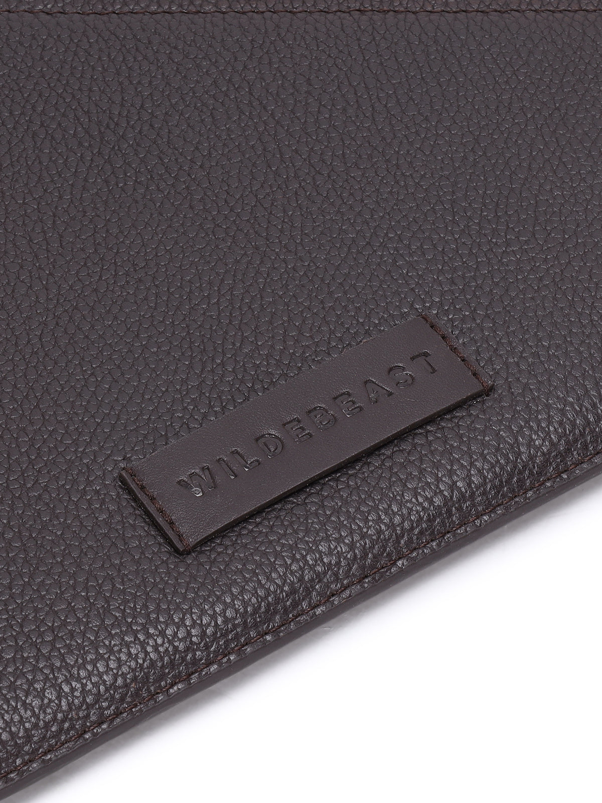 Close-up of the debossed Wildebeast logo patch on The Envoy brown leather sleeve