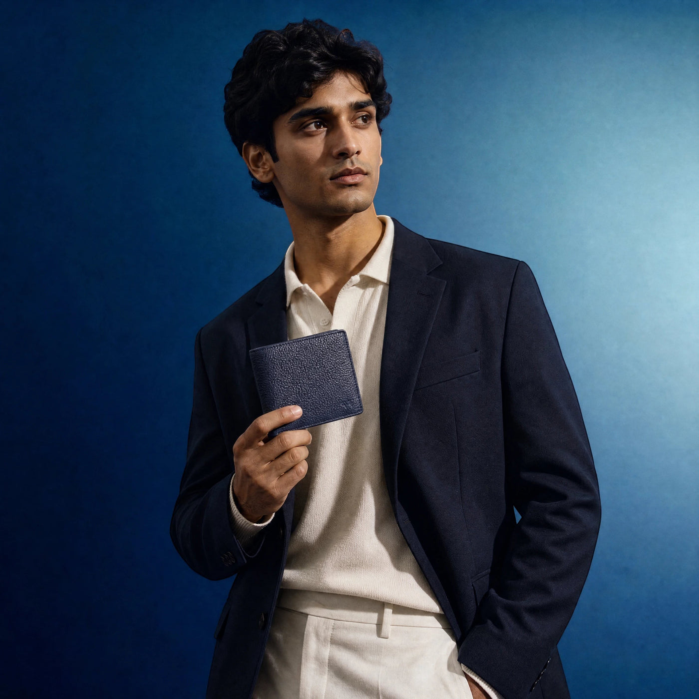 Wildebeast The Frontier navy blue leather wallet held by a man in a blazer against a blue background