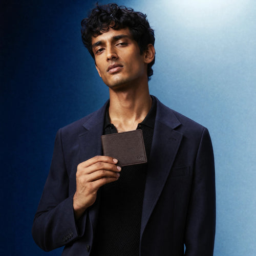 Wildebeast The Nomad brown European leather wallet held by a man in a navy blazer