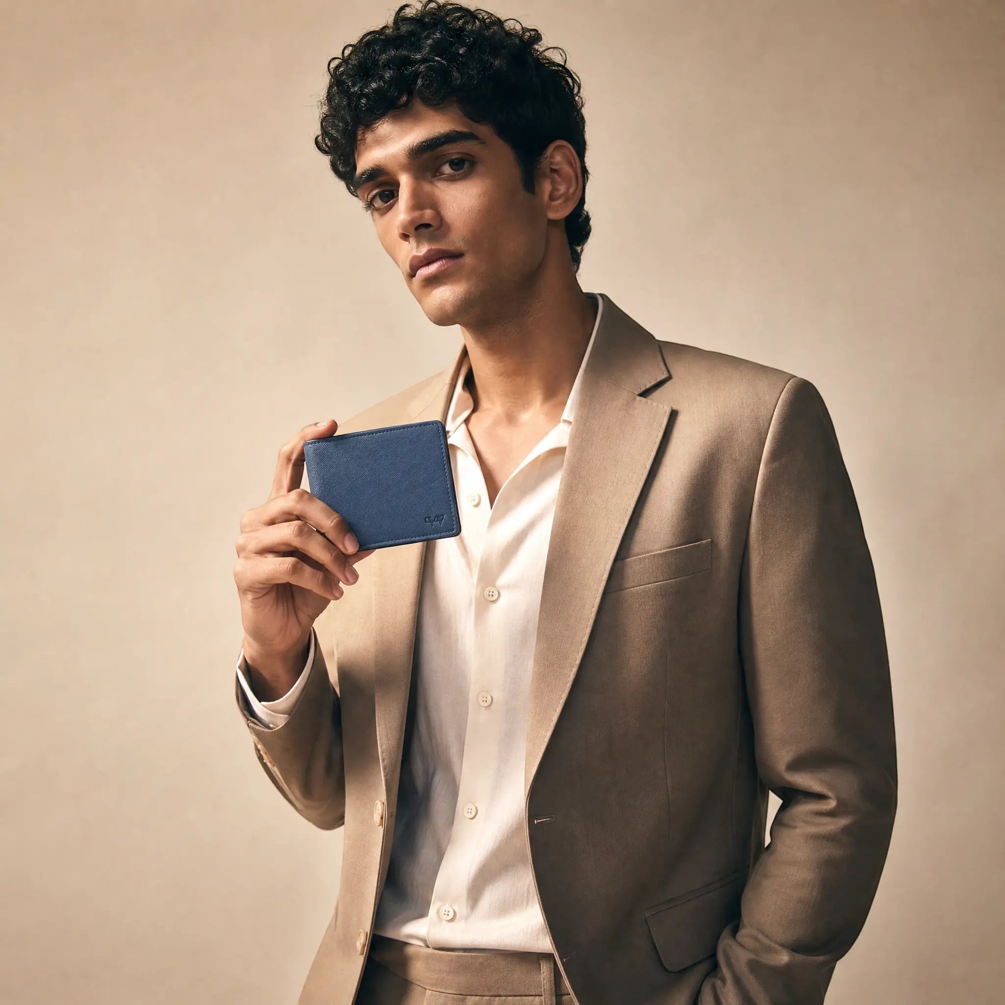Wildebeast The Edge blue Saffiano leather bifold wallet held by a man in a beige suit